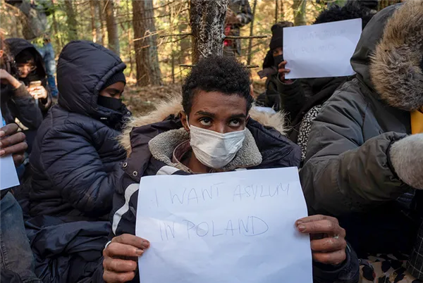 Мигрант из Сомали держит листок с надписью «Хочу убежище в Польше». Другие мигранты хотят попытать счастья в западной части Европы 